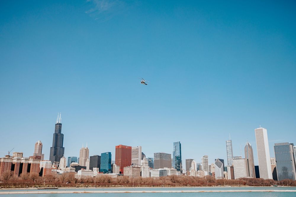 Chicago skyline with Willis Tower under clear blue sky, viewed from Lake Michigan shoreline.