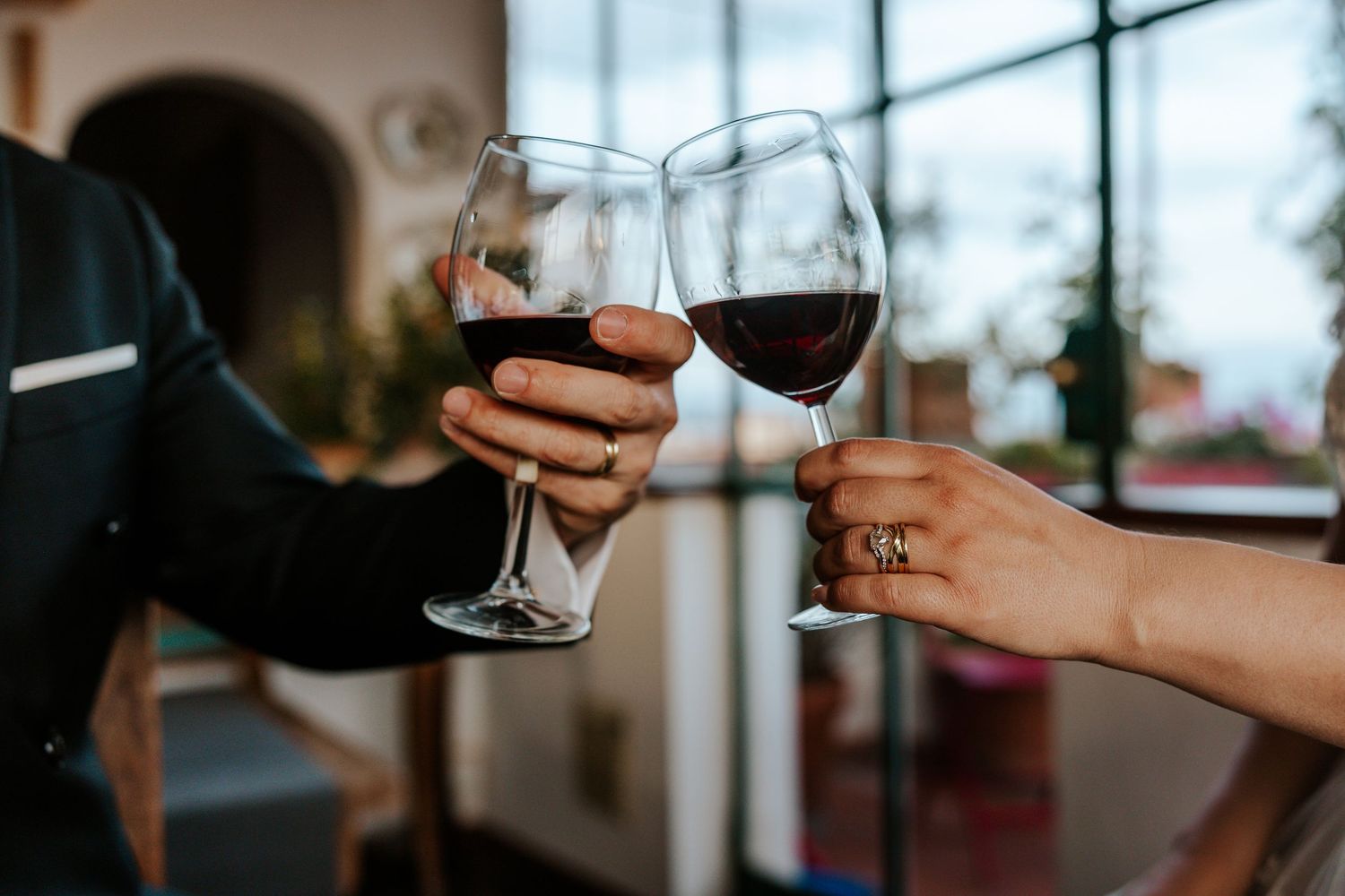 couple clinking glasses of red wine together during elopement day