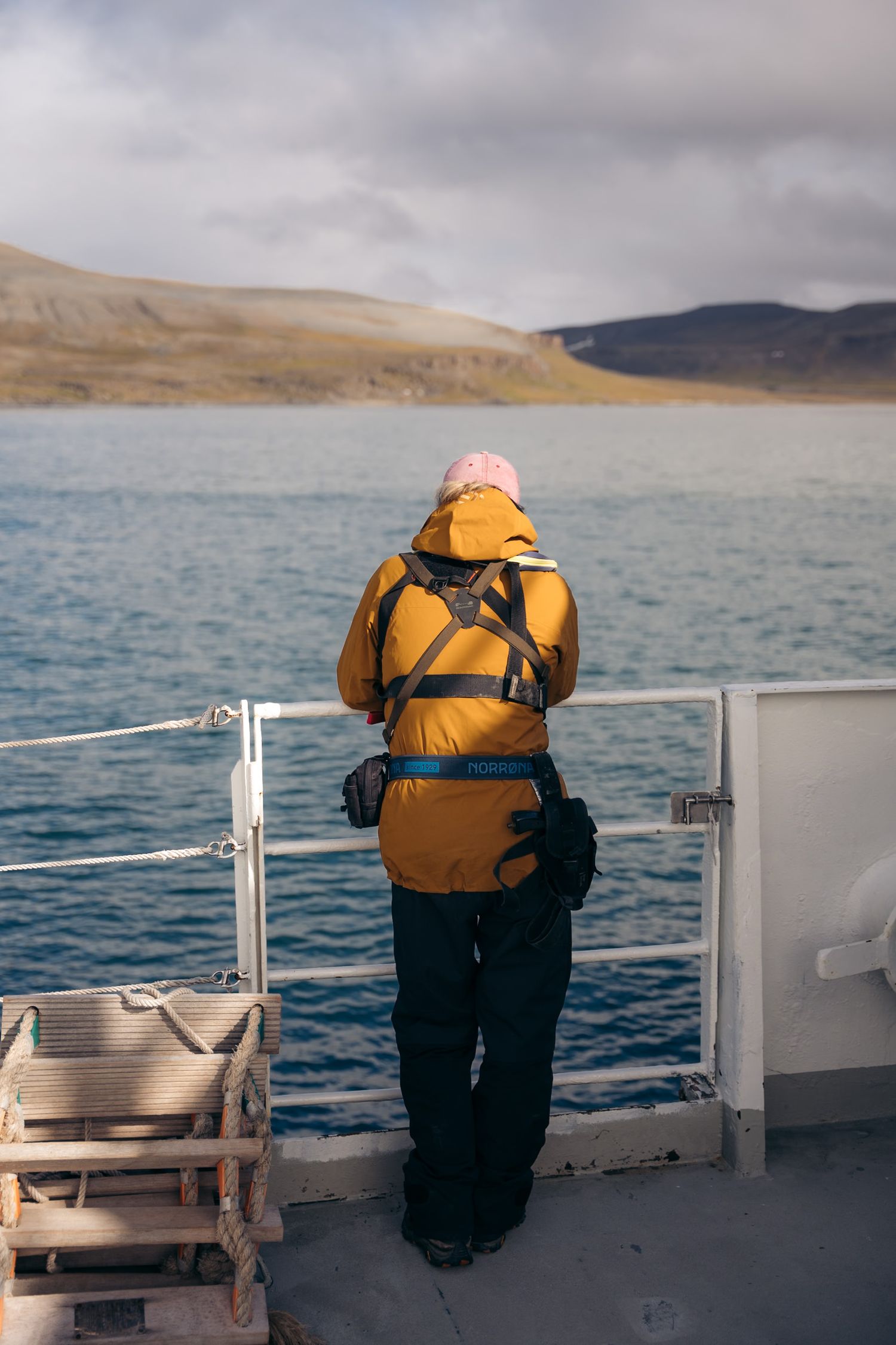 passager de dos sur le pont du polarfront en train de regarder la mer et les fjors du svalabrd en arrière-plan
