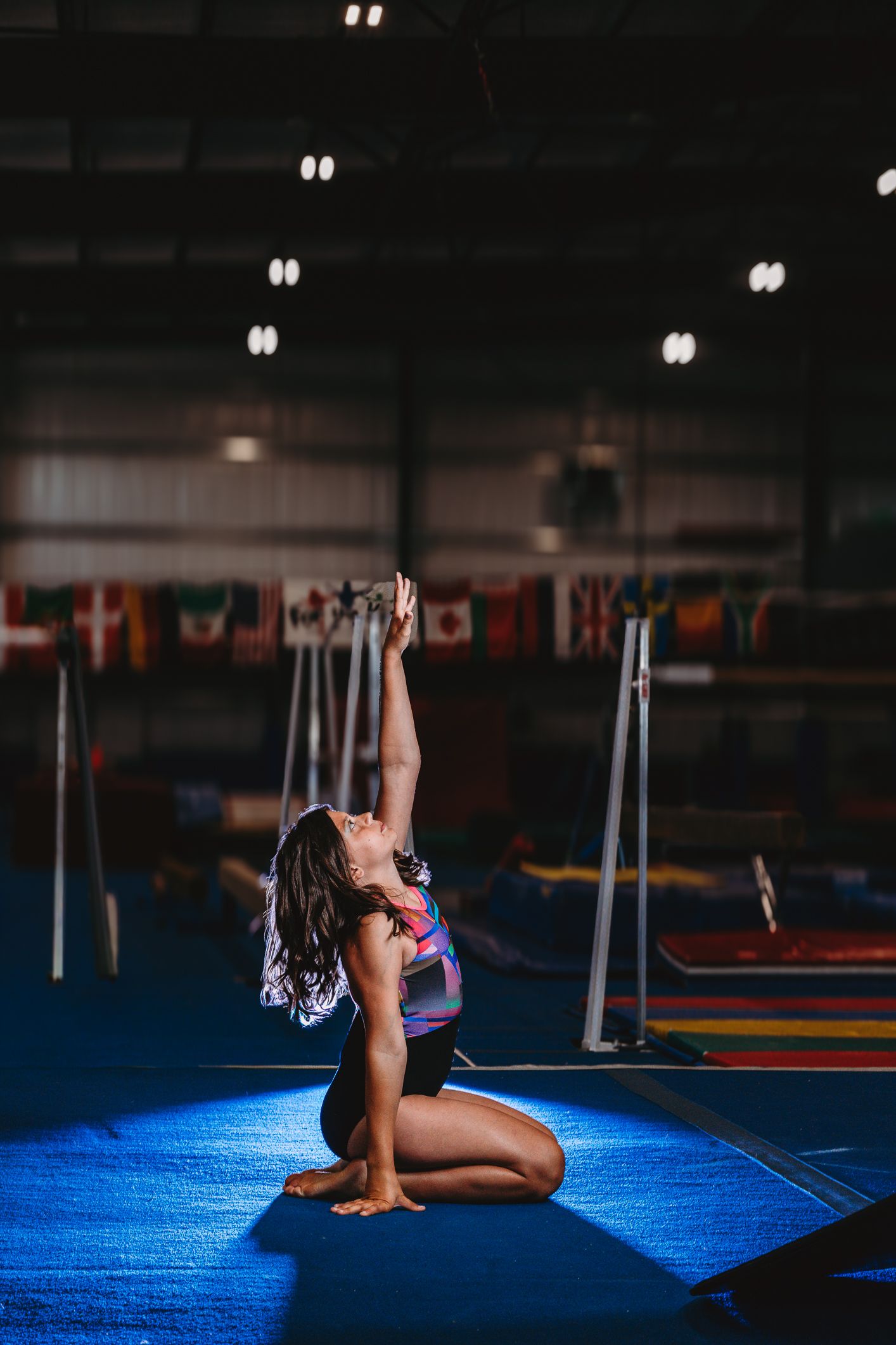 Young girl in smiley face swimsuit blowing chalk powder from her hands in a gymnastics gym.