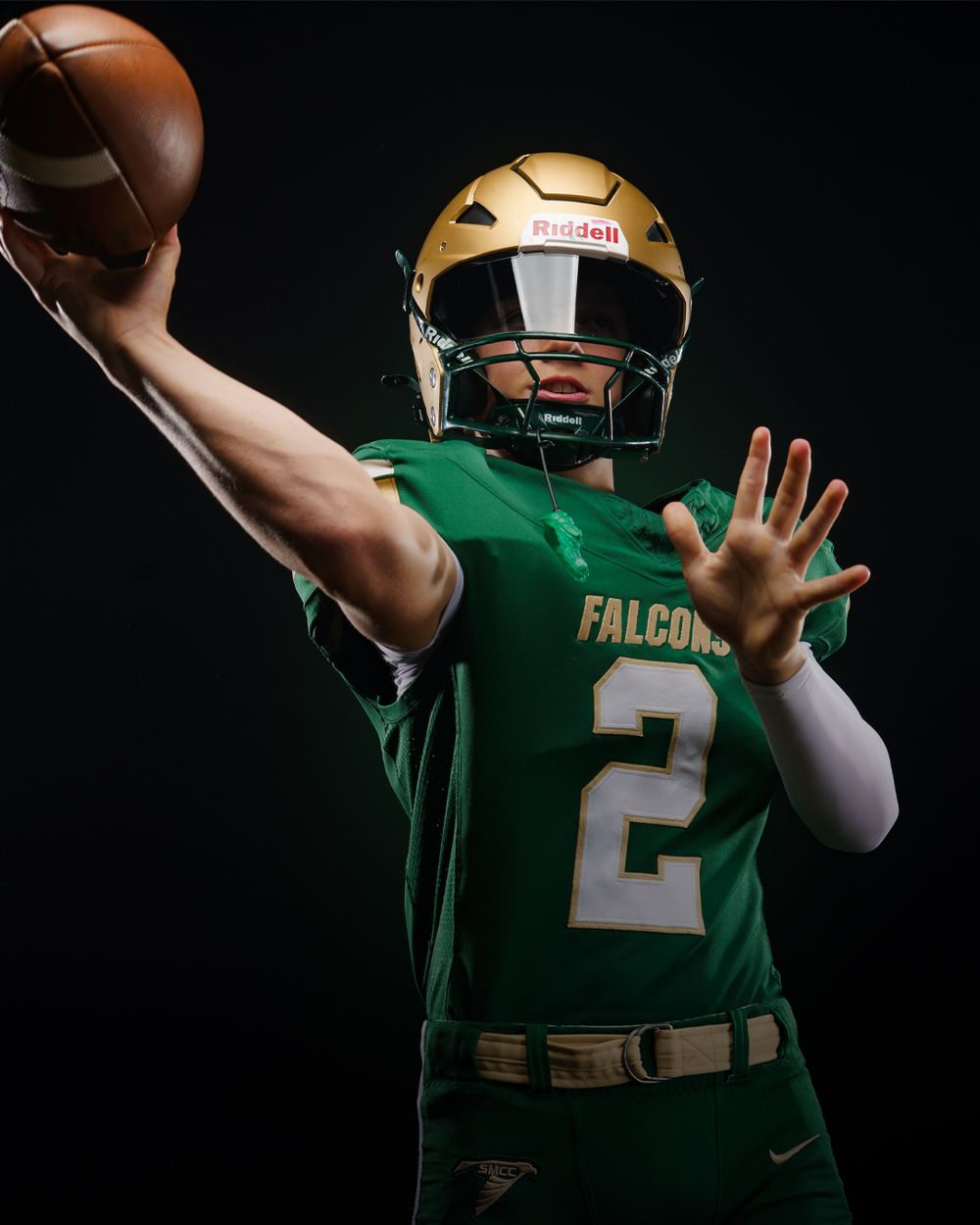 Falcons #2 quarterback in green and gold uniform throwing football against dark background.