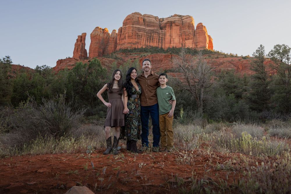 Family of four posing together in front of Cathedral Rock red rock formation in Sedona, Arizona.