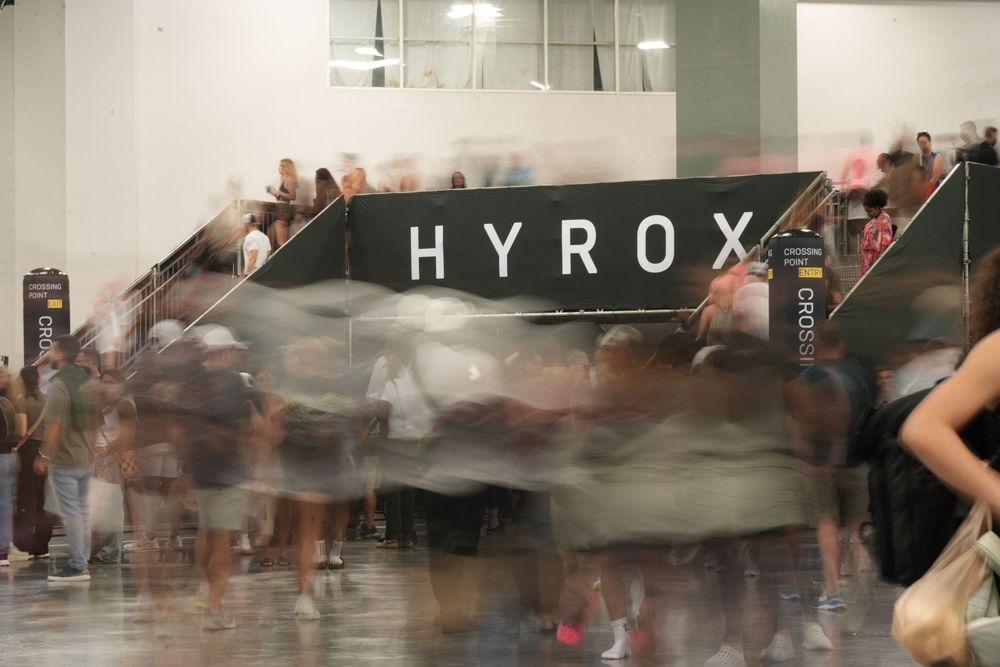 Long exposure photography capturing the energy and movement of spectators at a Hyrox fitness competition venue.