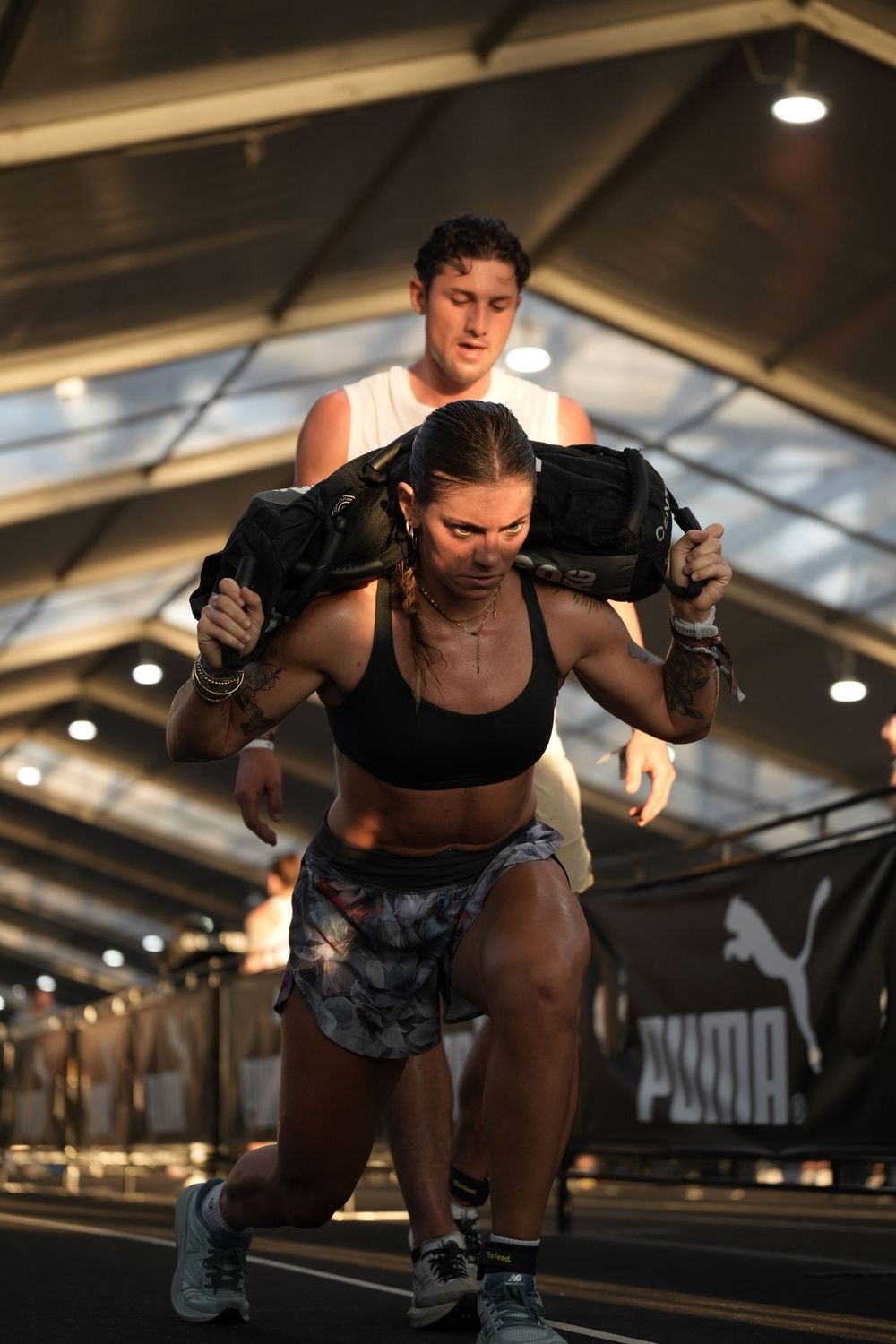 Hyrox athlete performing sandbag lunges at sunset, showcasing strength, endurance, and determination in functional fitness race.