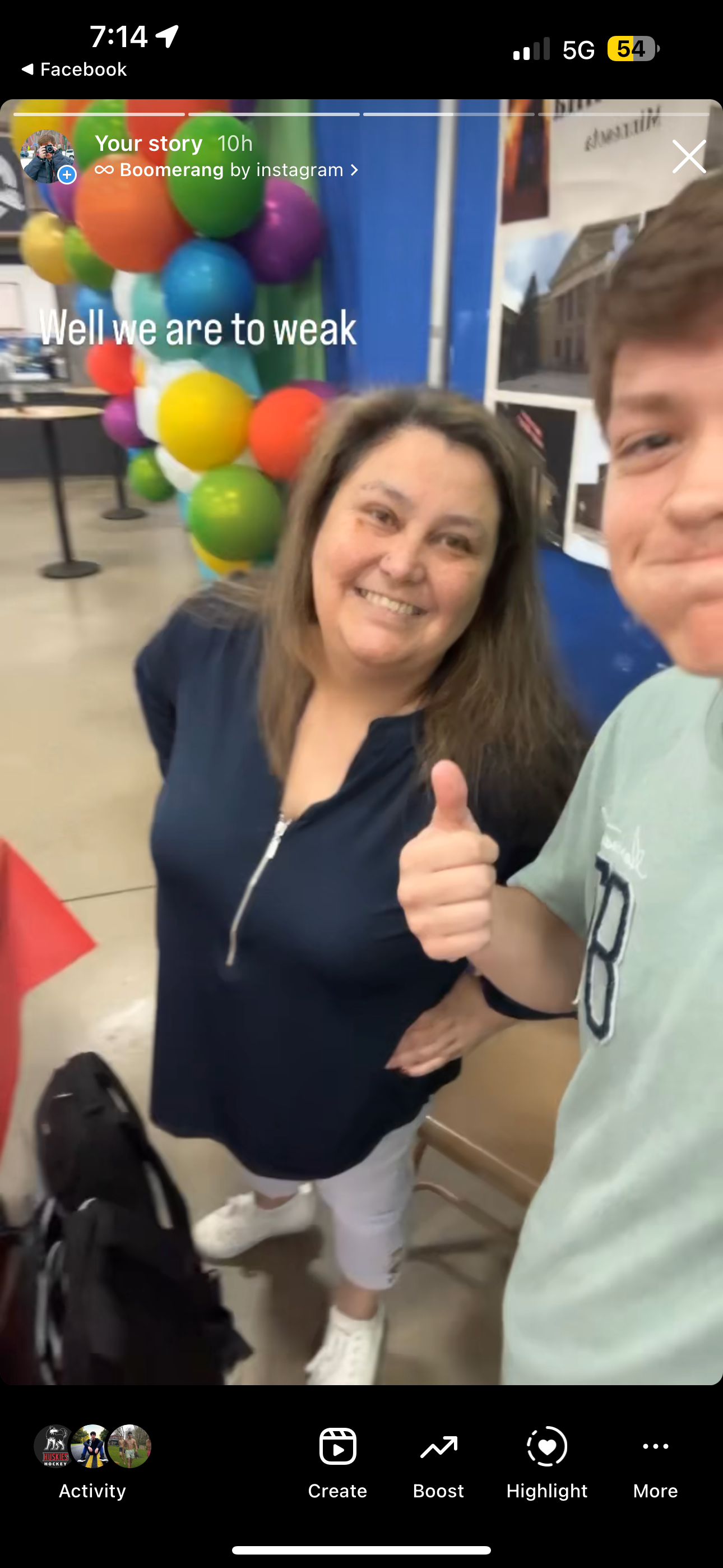 Two people smiling and giving thumbs up at a colorful balloon-decorated event, captured in a Facebook story selfie.