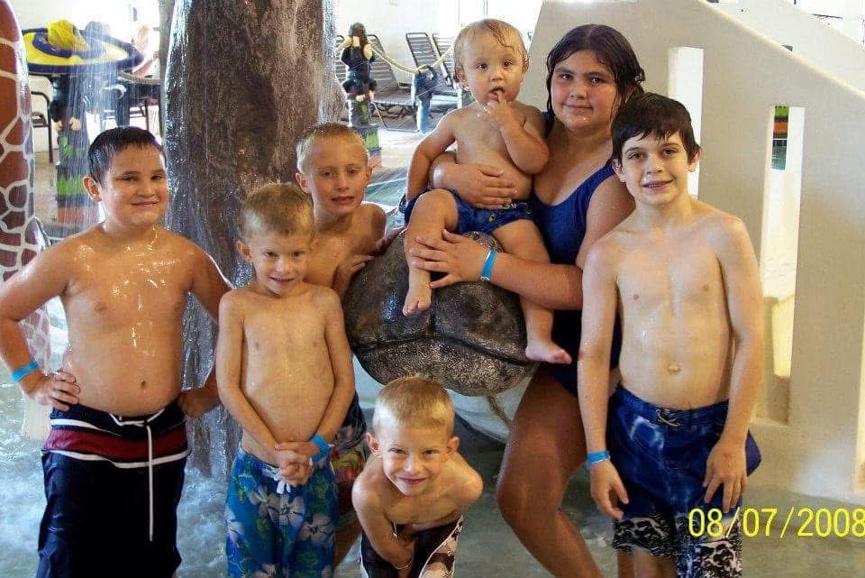 Group of children and a teenage girl posing at an indoor water park in 2009.
