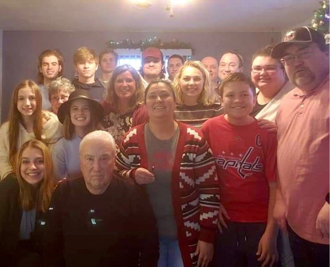 Large family group photo taken indoors during a Christmas holiday gathering, with adults and teens smiling together.