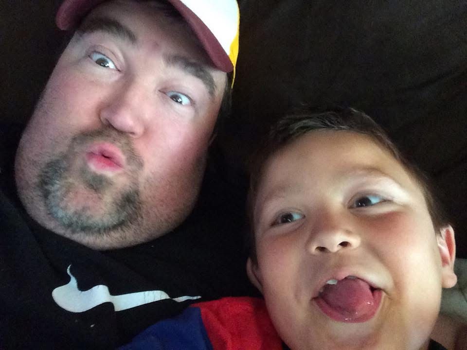 A man and young boy make silly faces together in a fun selfie photo.
