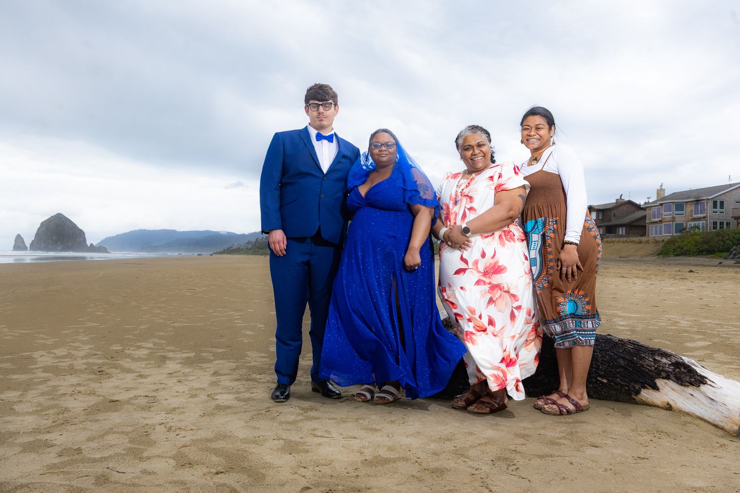 Family of four posing on a sandy beach near Cannon Beach, Oregon, dressed in formal attire with Haystack Rock in background.