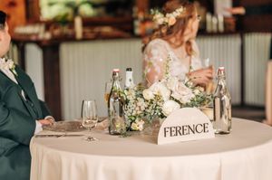 Elegant wedding sweetheart table with white floral centerpiece, water bottles, and Ference name sign.
