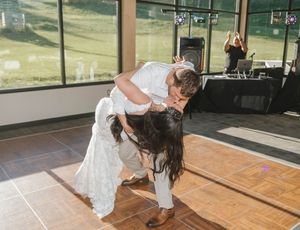 Bride and groom share a romantic dip kiss on the dance floor during their wedding reception.