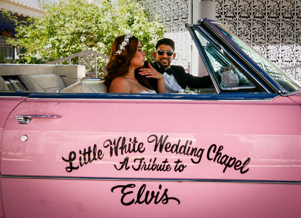 Couple in wedding attire sitting in a pink Little White Wedding Chapel Elvis tribute convertible car in Las Vegas.