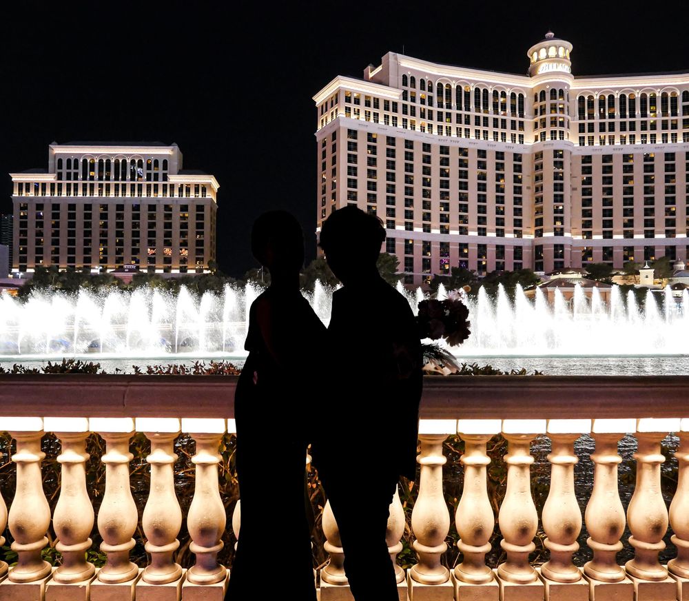 Couple silhouetted against the Bellagio fountains and hotel at night in Las Vegas.