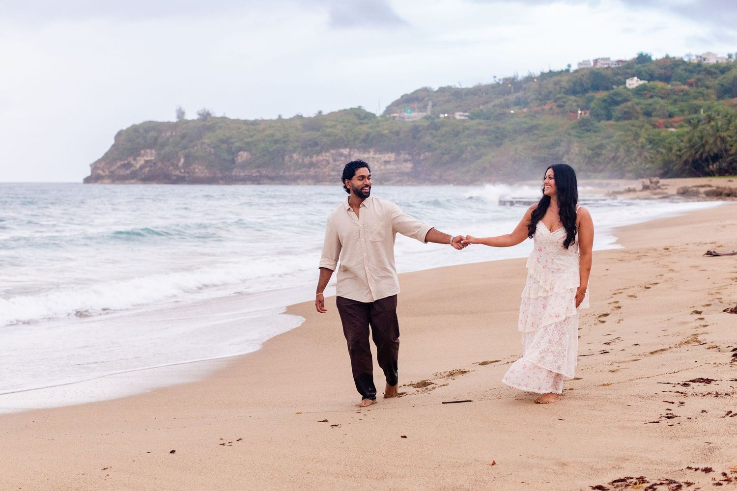 Engagement portrait on the beach. Man and woman walking along the shore. Playa Guajataca, Isabela, Puerto Rico.