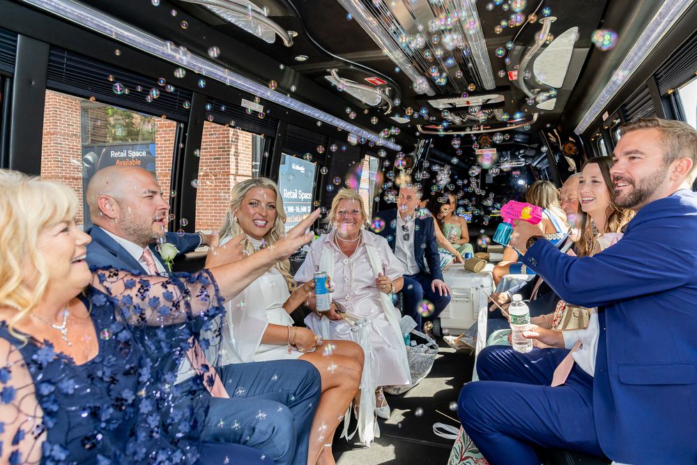 Wedding party celebrating with confetti inside a luxury party bus, guests in formal attire toasting with drinks.