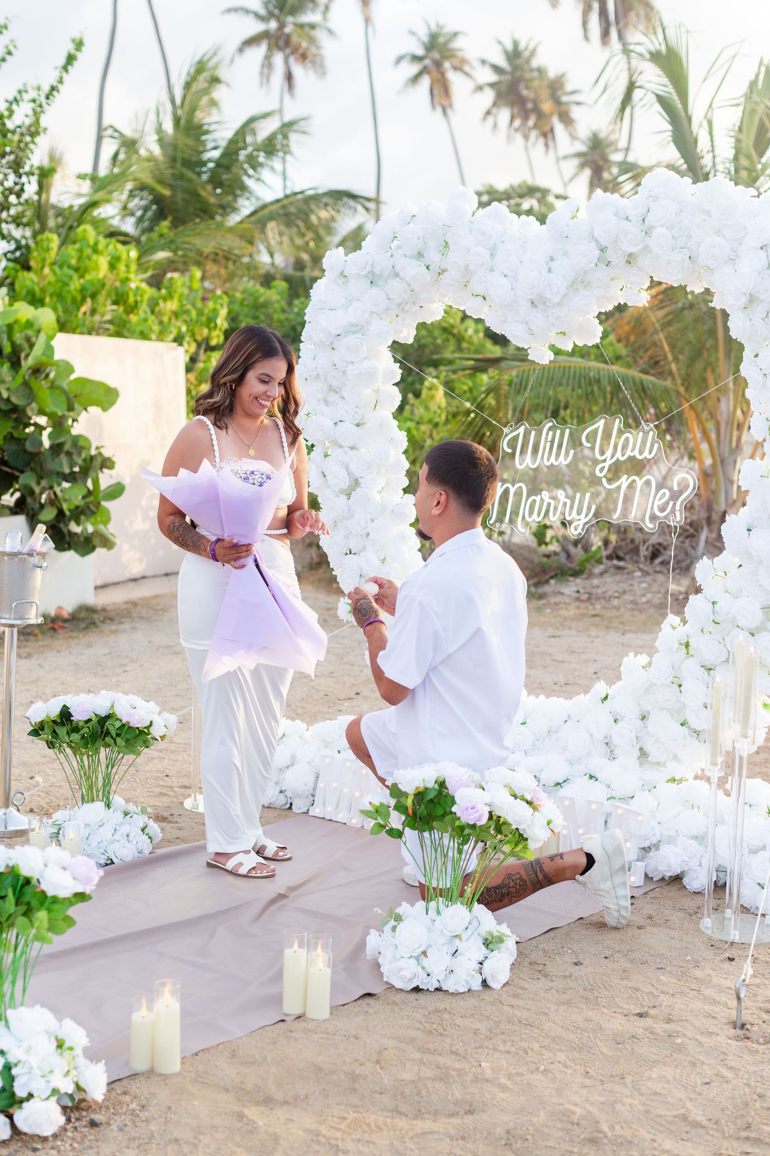 Marriage proposal. Man, woman, and decorative setup with white flower heart overlooking the ocean in Río Grande, Puerto Rico.
