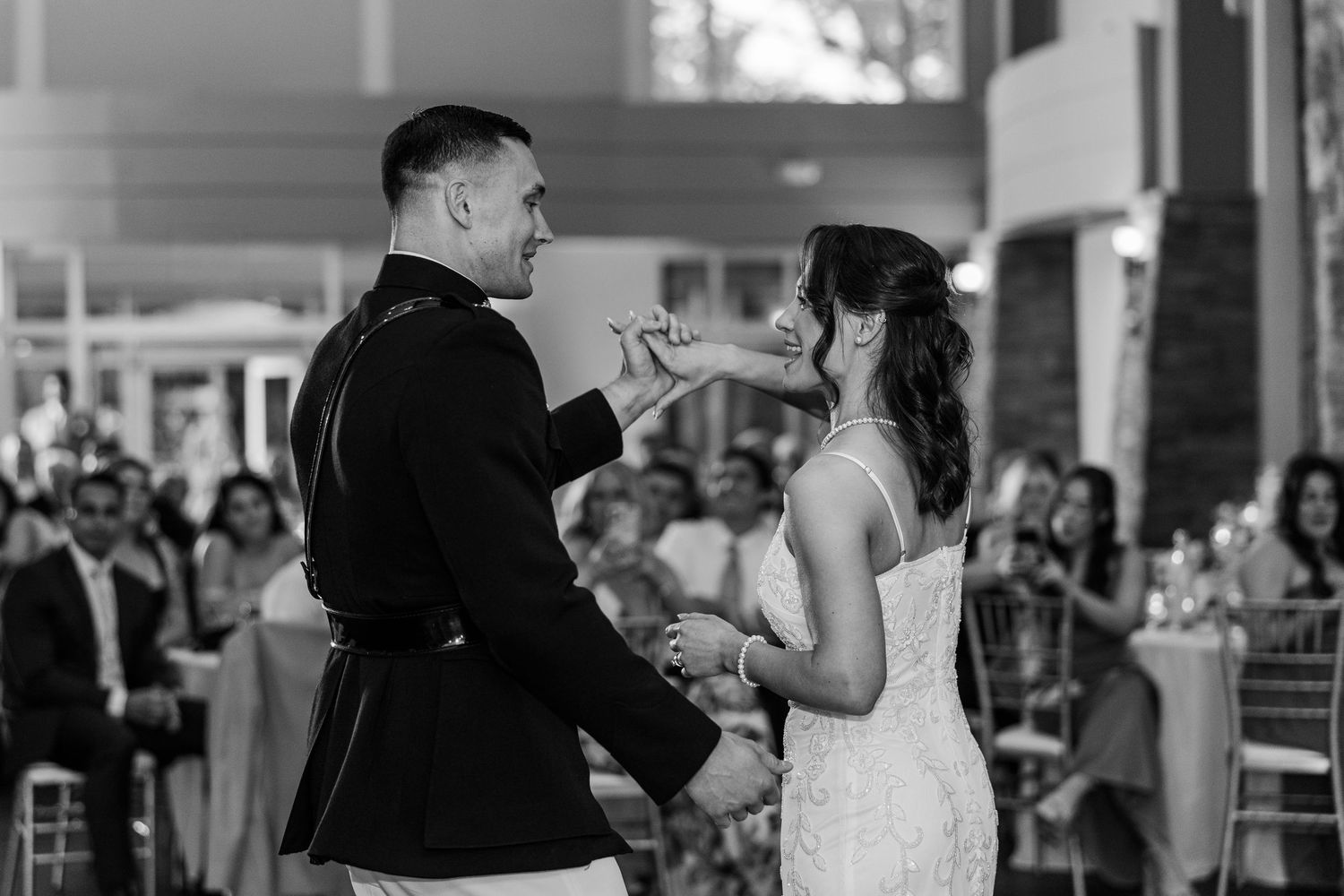 Black and white photo of a bride and groom sharing their first dance at a wedding reception.