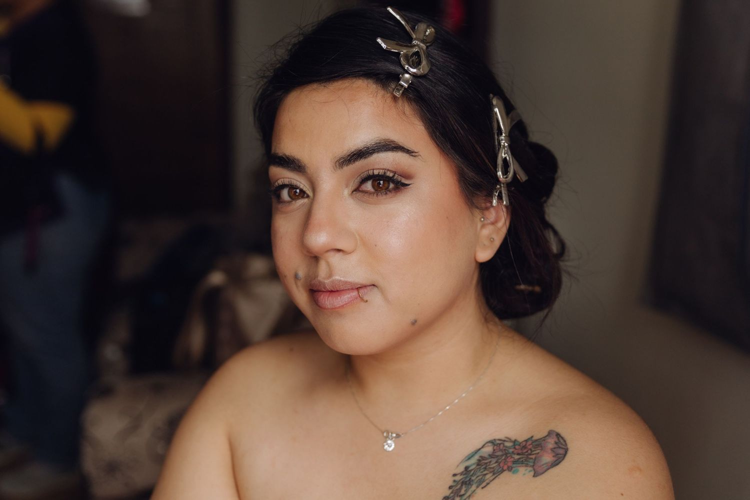 Beautiful bride with floral hair accessories and tattoos showcases her completed bridal makeup look.
