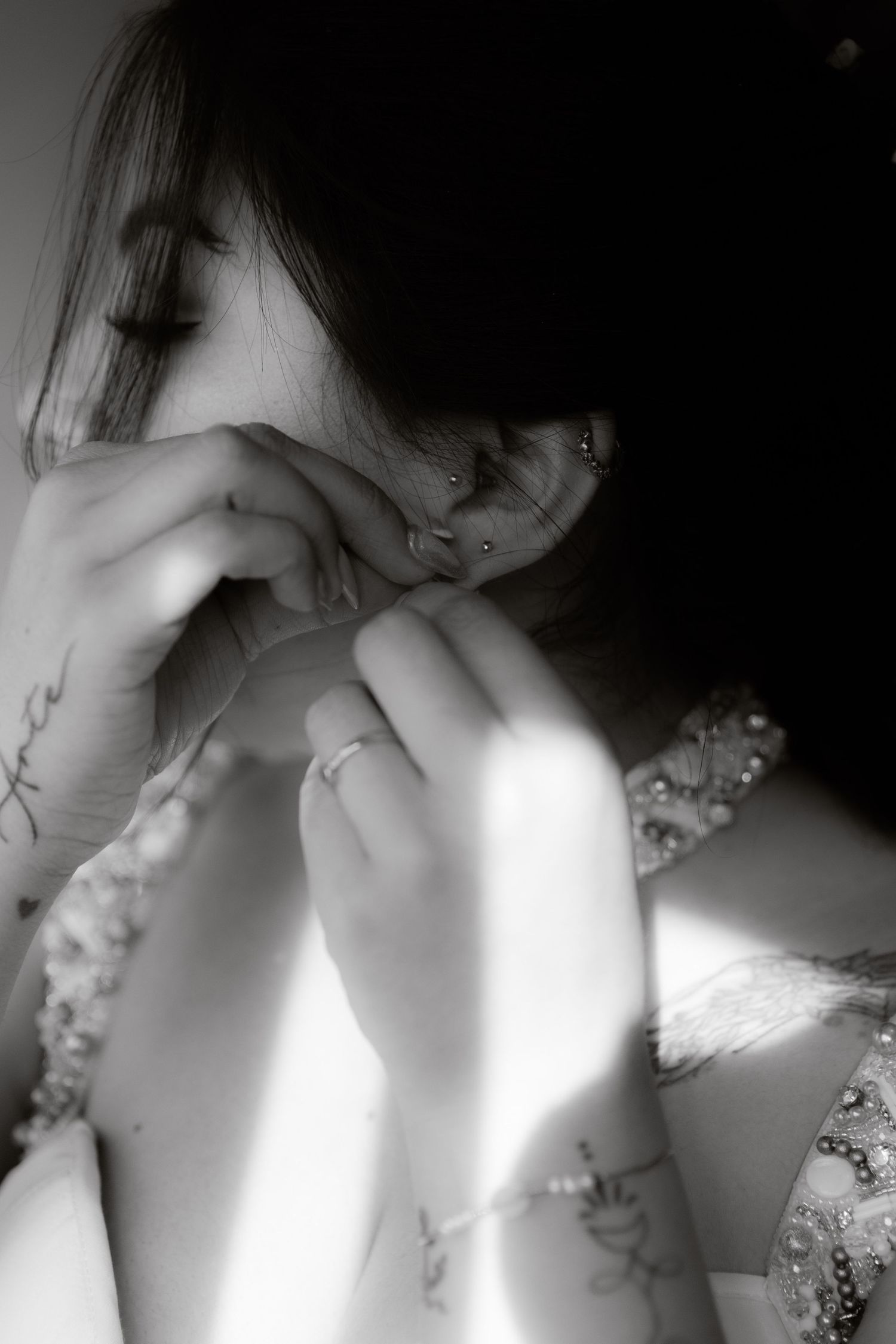 Black and white photo of a bride putting on earrings while getting ready for her wedding day.