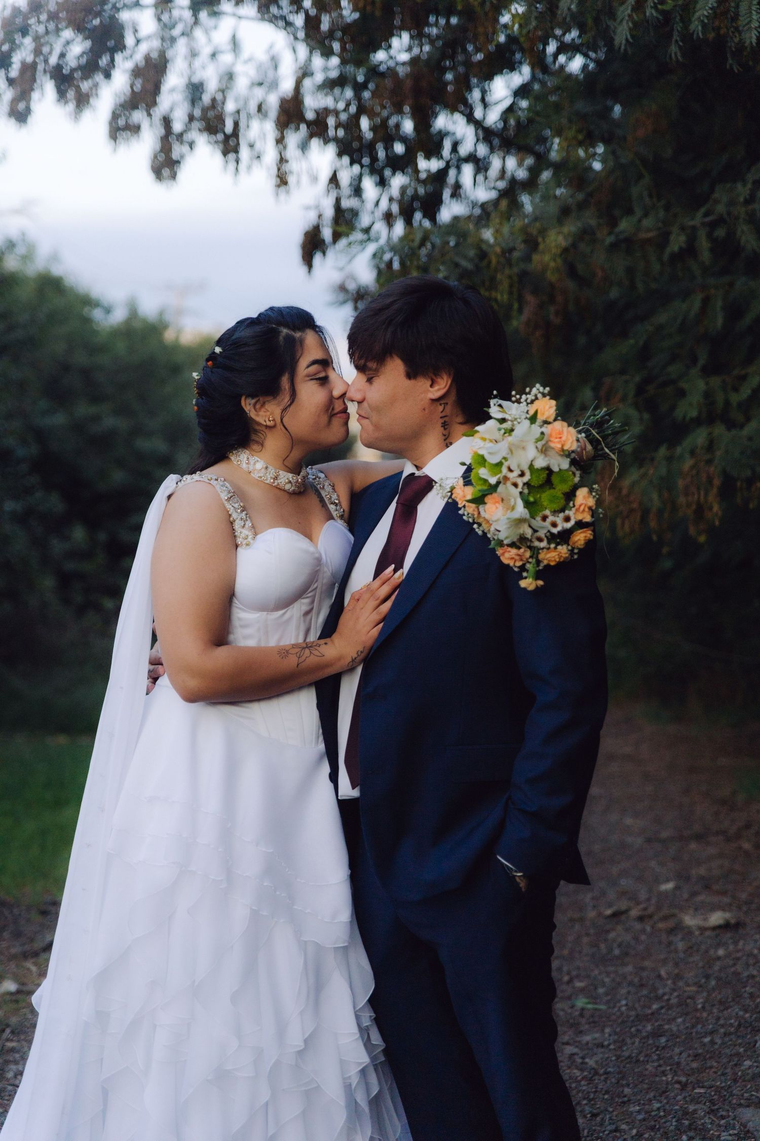 Bride and groom sharing an intimate moment outdoors, bride in layered white gown with veil.