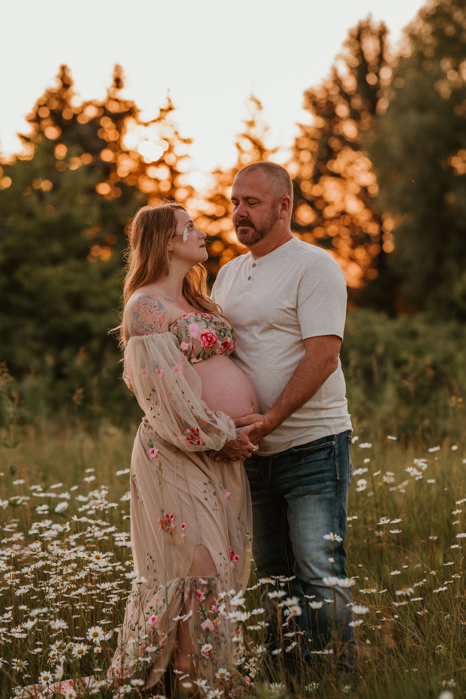 Black and white maternity photo of a couple tenderly cradling a pregnant belly in an outdoor setting.