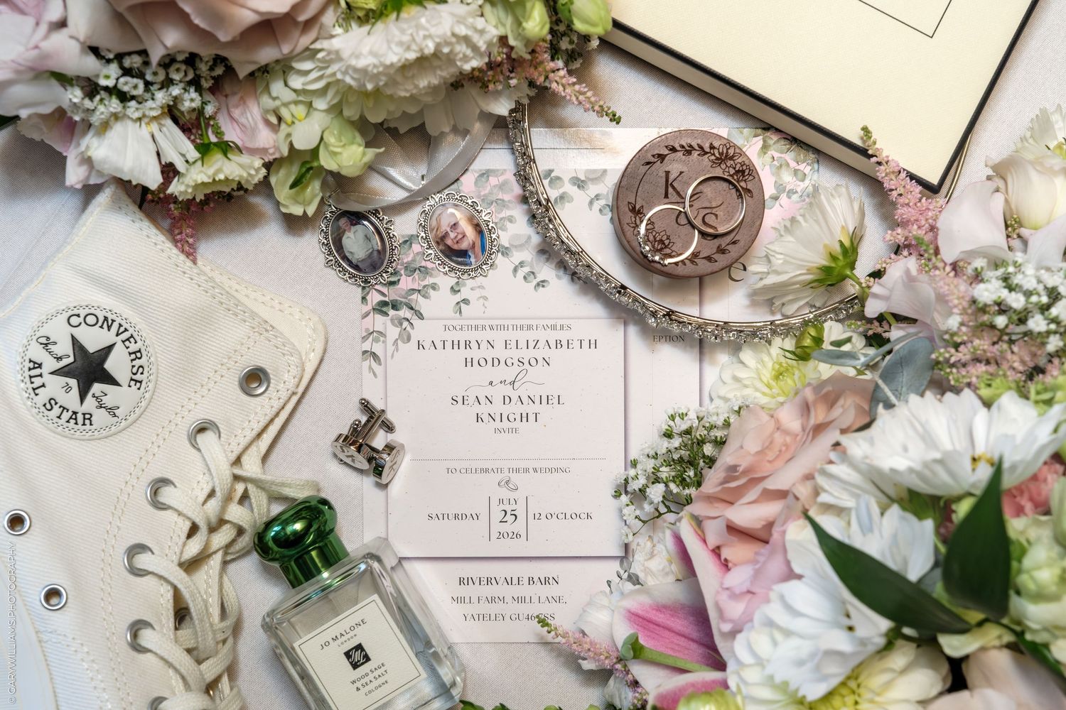 Wedding flat lay with floral bouquet, Converse sneakers, Jo Malone perfume, rings, jewelry, and elegant invitation suite.