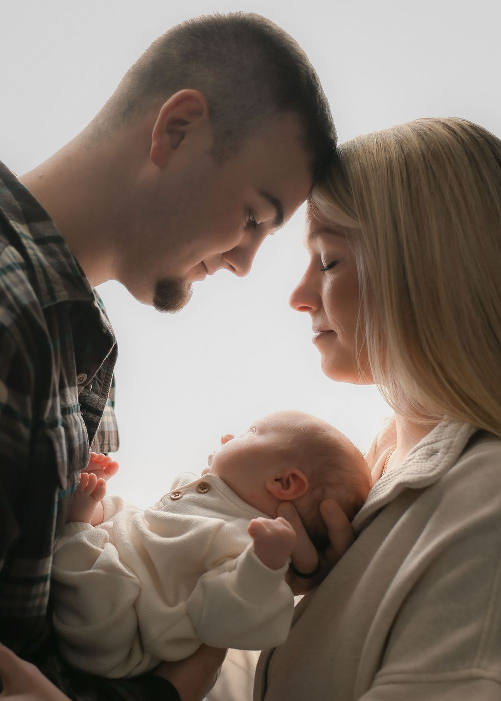 A couple tenderly gazes at their newborn baby, sharing an intimate family moment together.