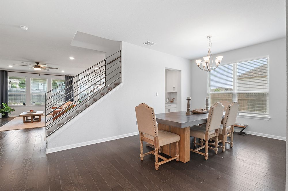 Open concept modern kitchen with white cabinets and stainless appliances flows into bright dining and living areas.