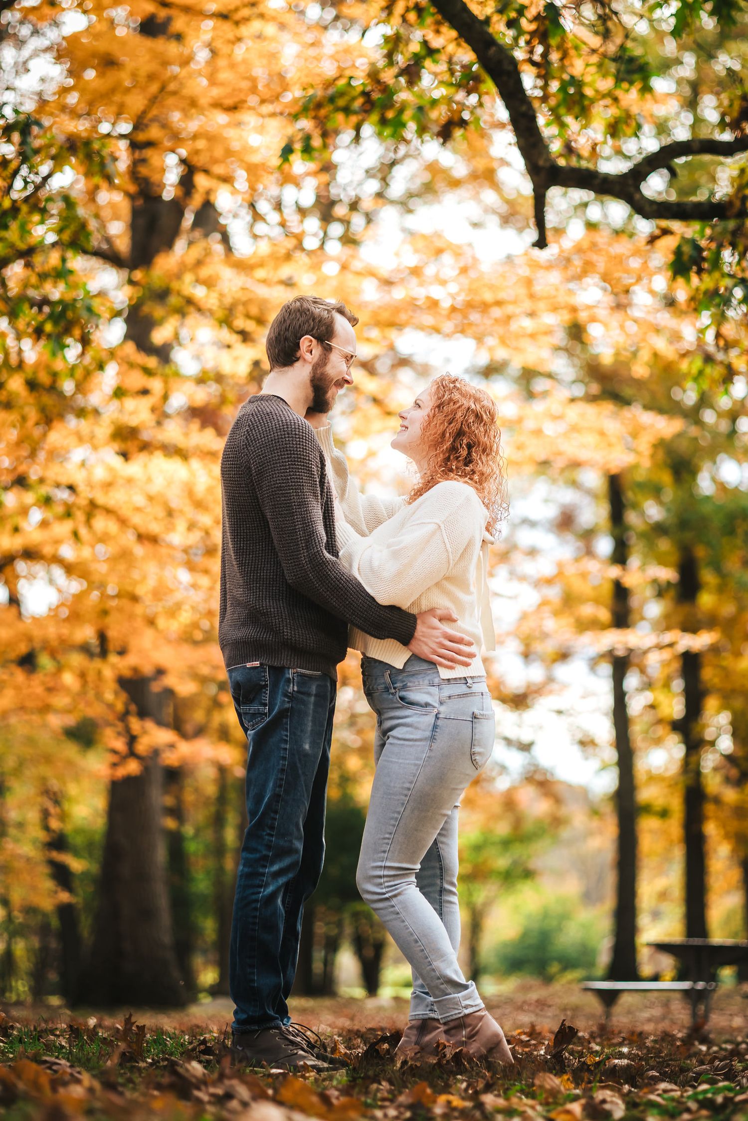Engaged couple laughing together on a trail at Borderland State Park, surrounded by fall foliage.