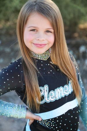 Smiling young cheerleader with long straight hair poses with a hand on her hip in a black Element cheer uniform with sparkling rhinestones.