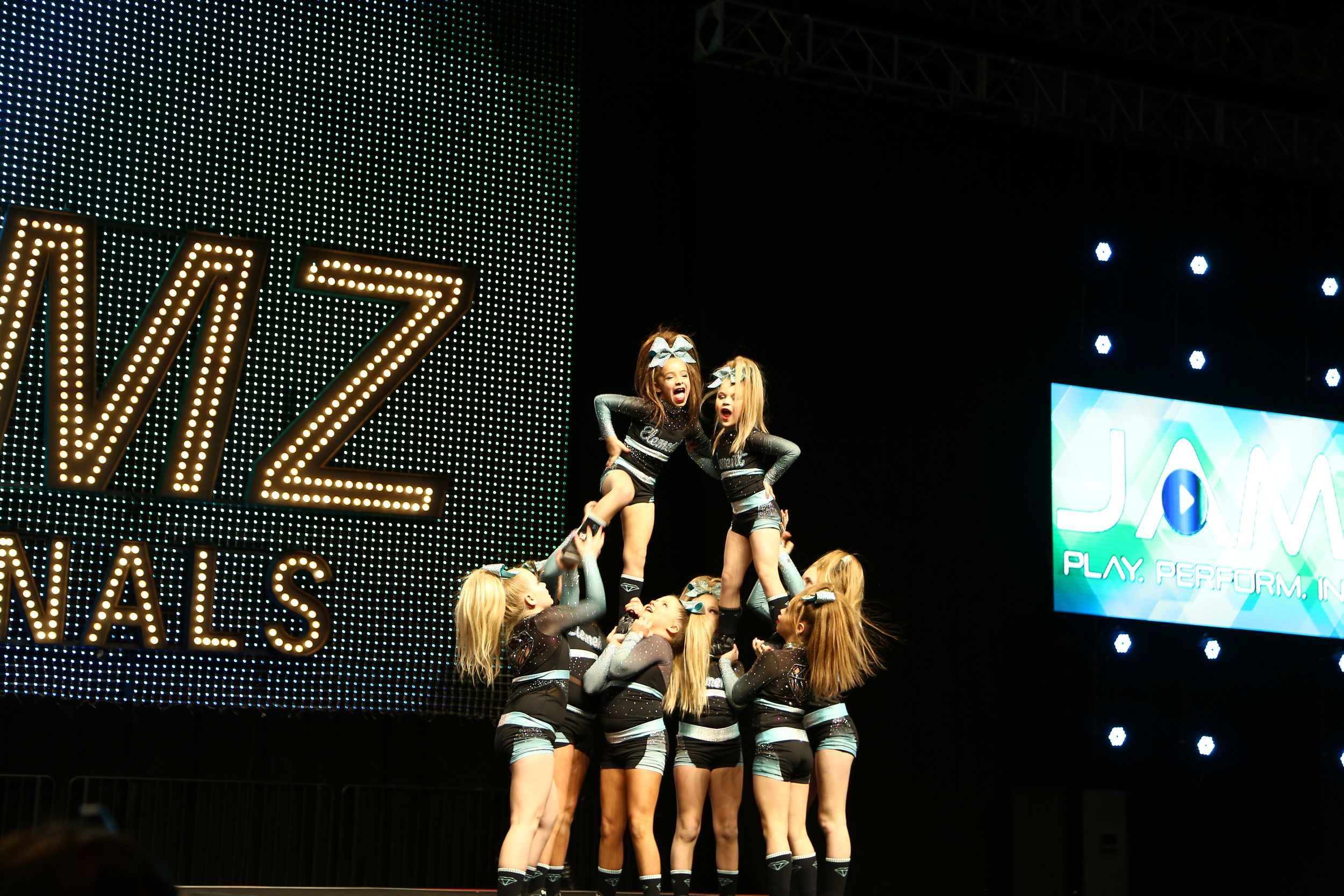 Cheerleaders lift a flyer into an extended pyramid formation during their routine at the JAMZ Nationals cheer event.