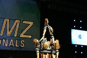 Cheer team holds a flyer high in a stunt as teammates support from below at the JAMZ Nationals competition.
