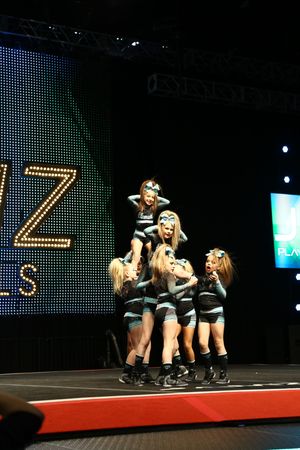 Youth cheerleaders form a stacked pyramid with a flyer on top during a competition routine at JAMZ Nationals.