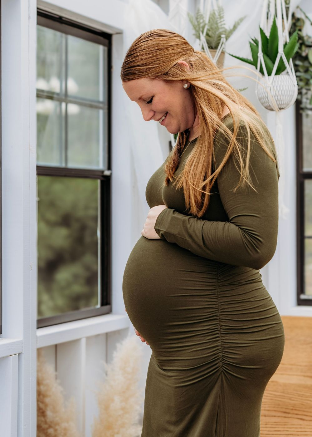 Expecting mother standing by a window during an greenhouse South Jersey maternity and family photography session.