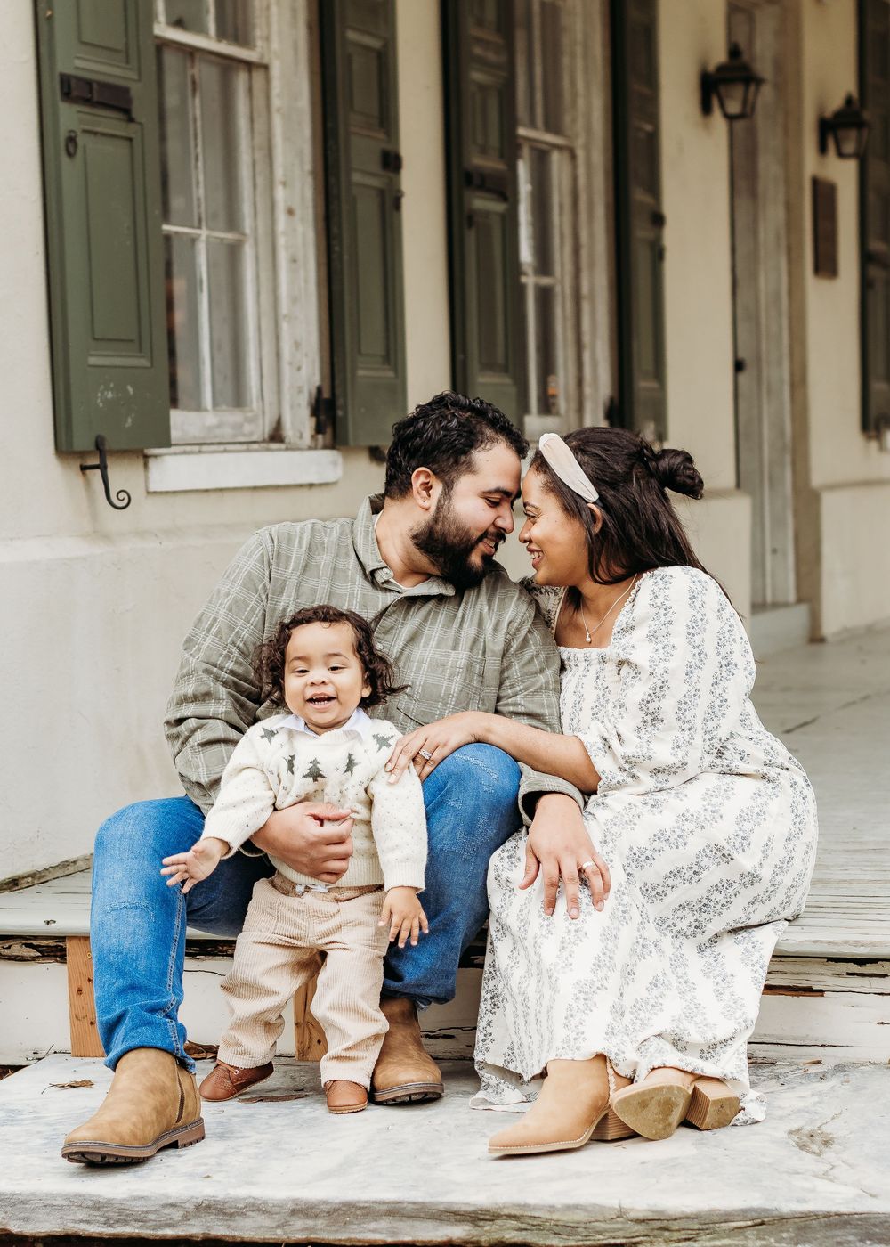Parents laughing with their toddler during a relaxed family photo session.
