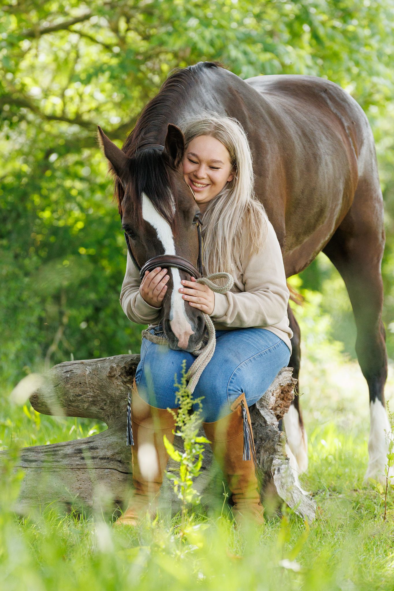 A man and woman smile at a farm gate surrounded by cattle and a horse in a lush green field.