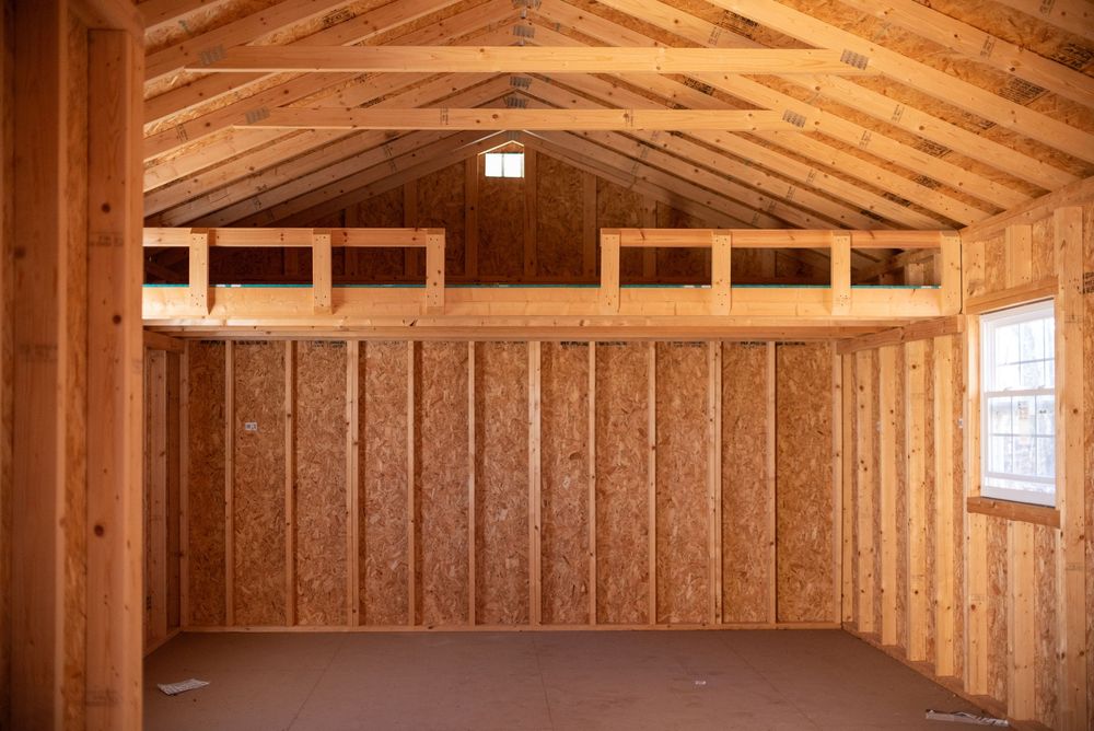 Interior of a wooden shed with vaulted ceiling, exposed rafters, and natural pine walls with a small window.