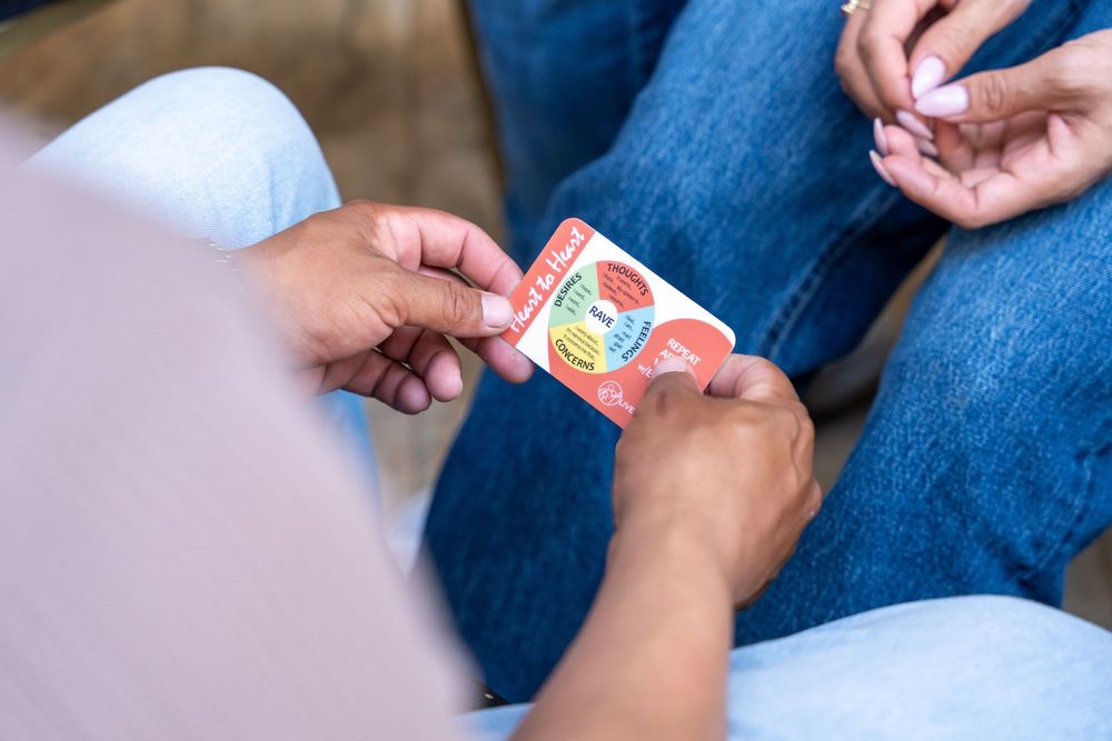 Two people exchanging a small red card, close-up view of hands passing an item while seated.