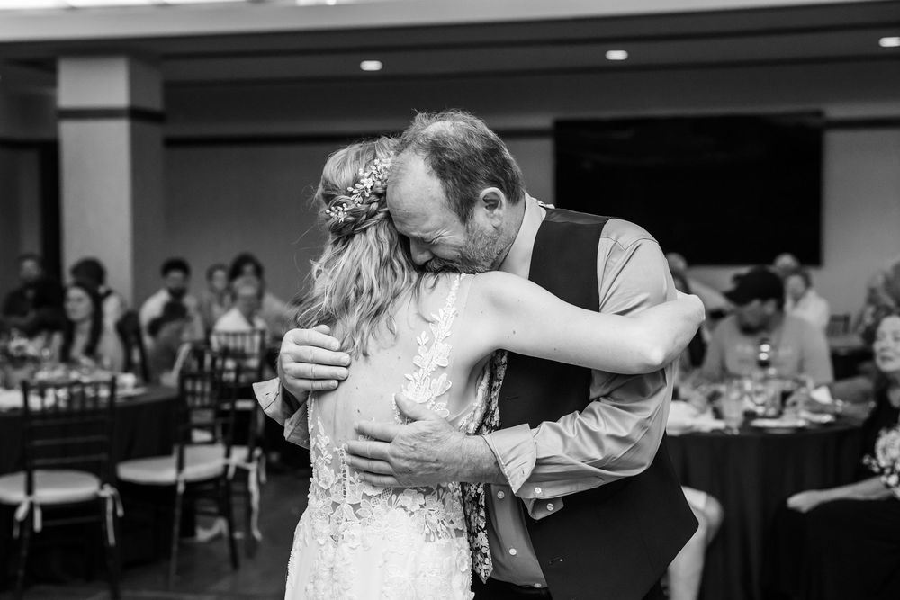 Bride and groom share a tender slow dance embrace at elegant wedding reception, captured in black and white.