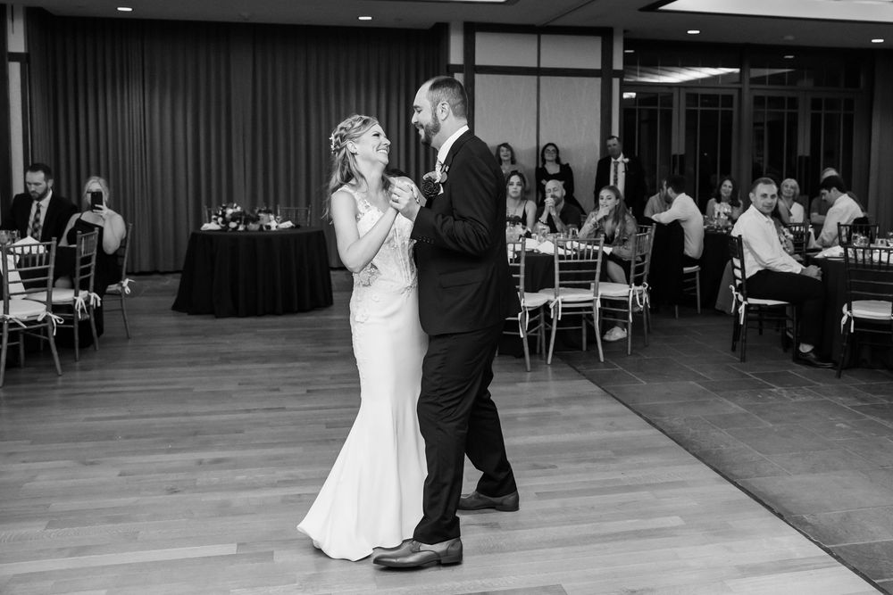Black and white photo of bride and groom sharing their first dance at elegant wedding reception.