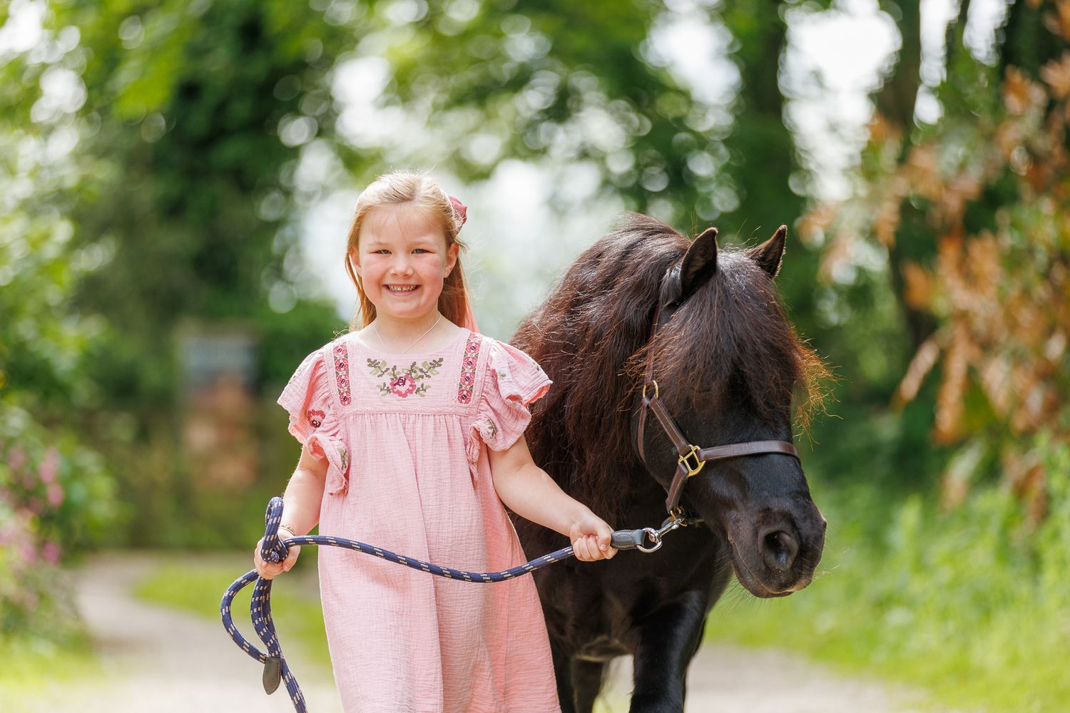 A horse and its rider enjoy an outdoor photoshoot session near rustic wooden fencing on a sunny day.