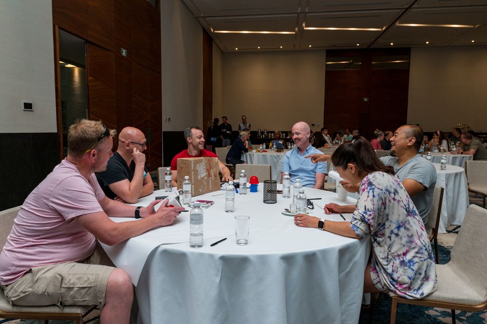People sitting around a round table in a conference room having a discussion at a business meeting event.