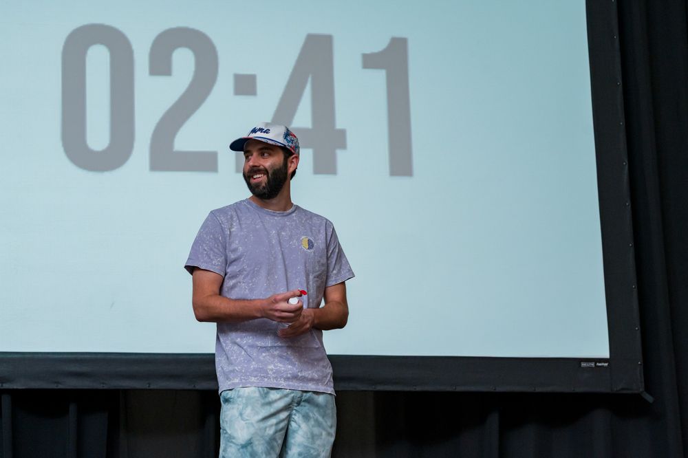 Man standing at podium presenting with a countdown timer showing 02:41 on screen behind him.