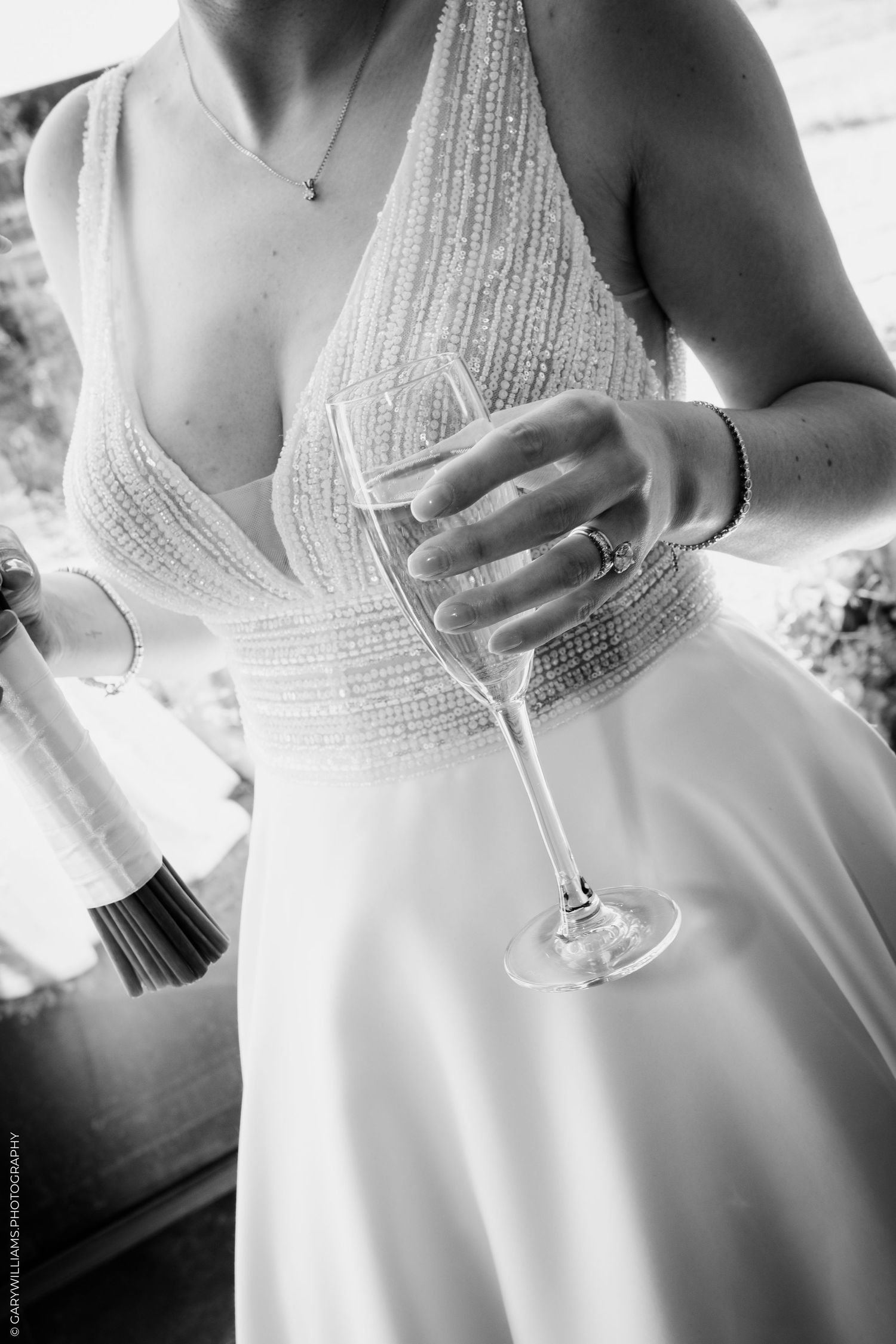 Bride in a beaded wedding gown holding a champagne flute, black and white wedding photography.