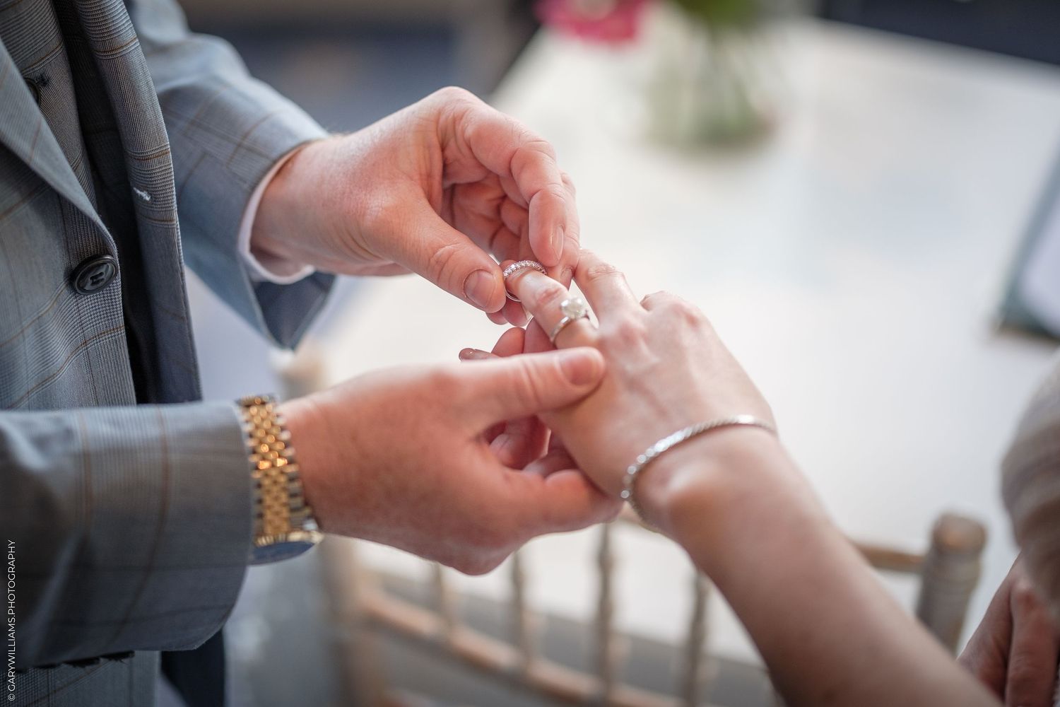 Close-up of a groom placing a wedding ring on the bride's finger during a wedding ceremony.