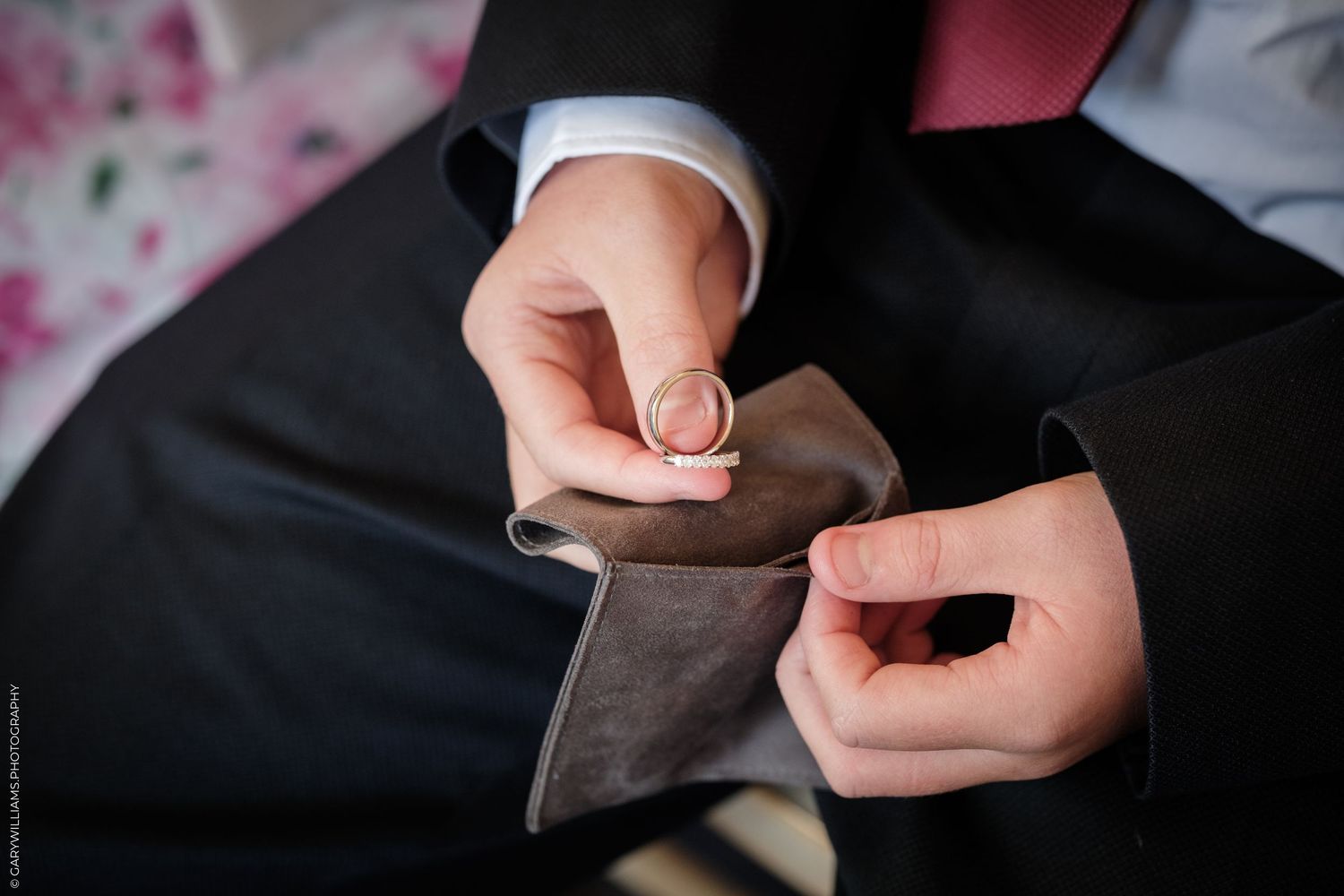 Close-up of a groom fastening a cufflink on his suit sleeve, preparing for a wedding ceremony.
