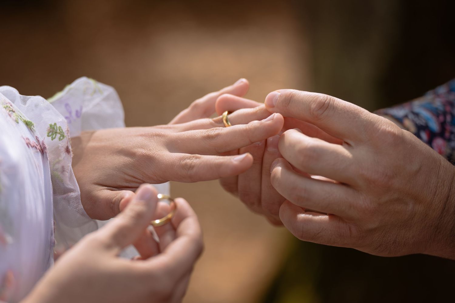 Gros plan d'un échange d'alliance, avec un marié posant une alliance en or au doigt de la mariée pendant la cérémonie.