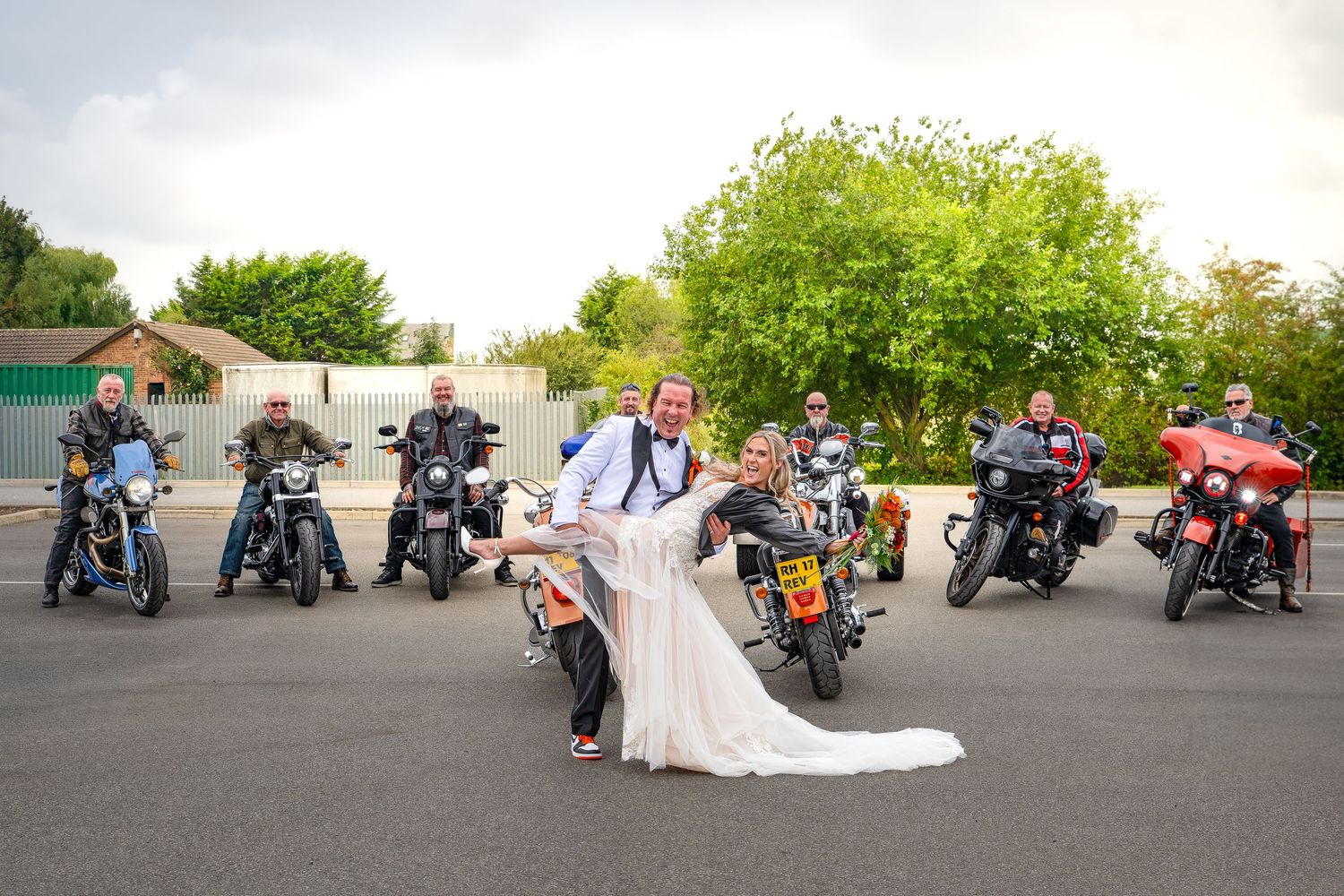 Bride and groom pose romantically in front of a group of motorcyclists on bikes at their wedding celebration Yorkshire,
