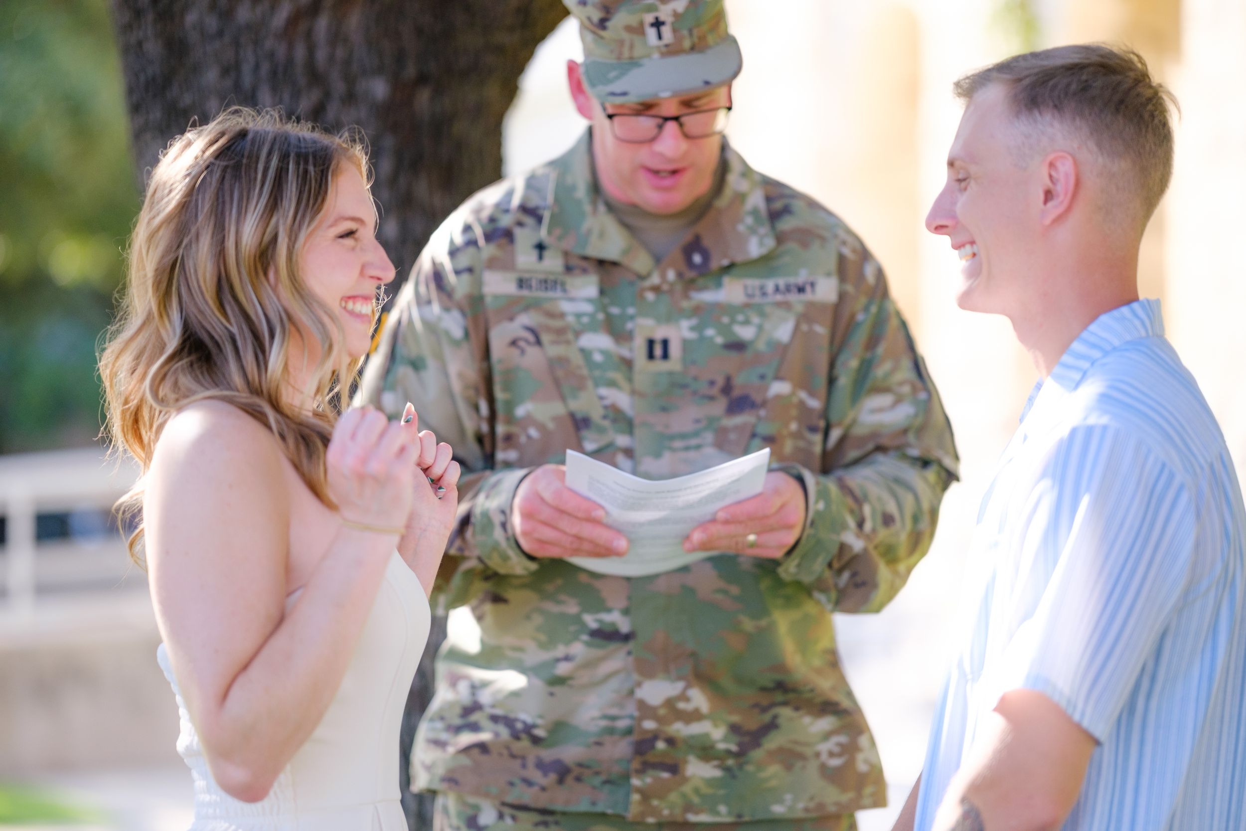 Joyful couple laughs during casual outdoor wedding ceremony with military chaplain officiating  in downtown Belton Texas at courthouse