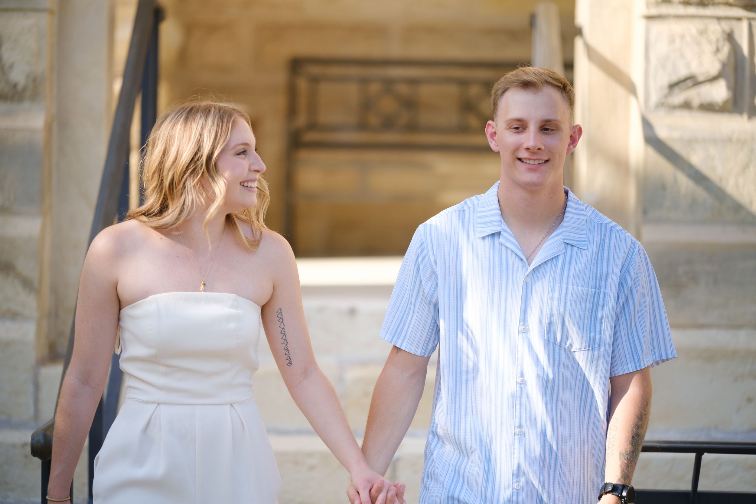 Newlywed couple holds hands and walks together smiling on sunny outdoor staircase steps  in downtown Belton Texas